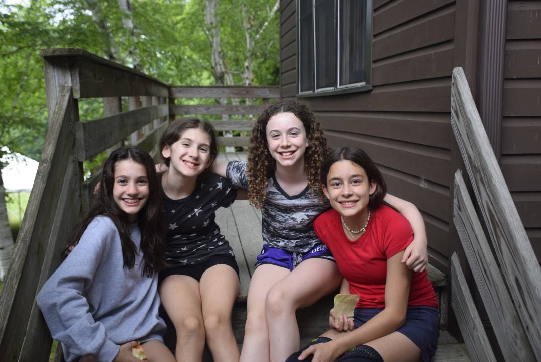 Children sitting outside a cabin