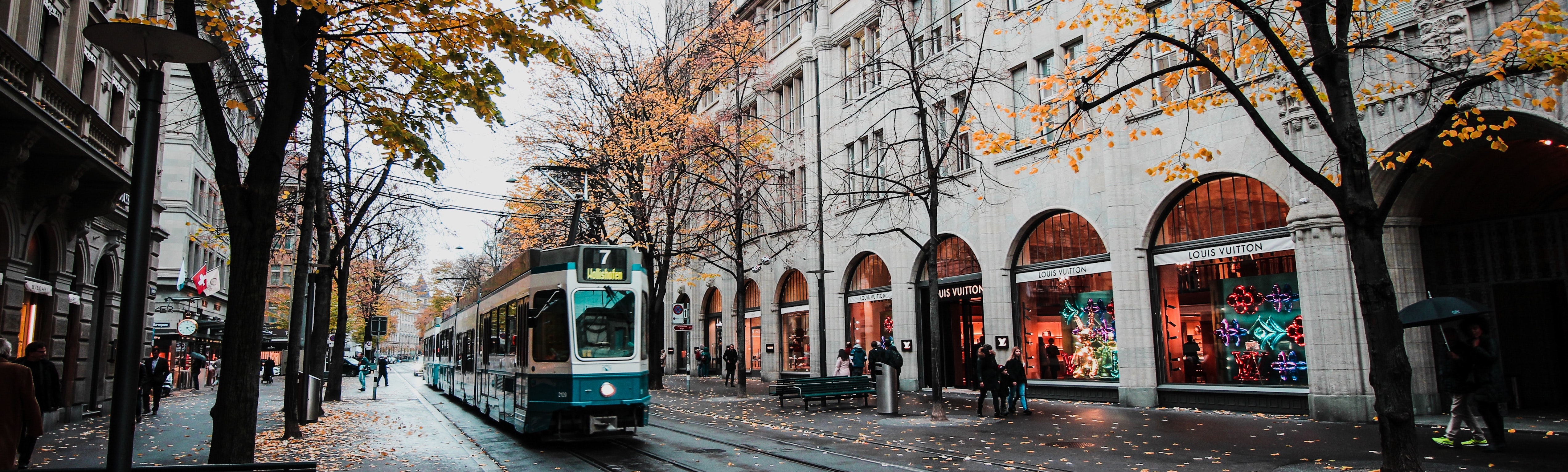 Street view of Amesterdam with tram driving in Fall season with yellow fallen leaves on the ground.